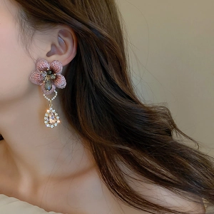 Elegant asymmetrical pink fabric flower earrings with sparkling rhinestone drop on model