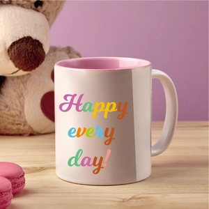Detail of a white ceramic mug with pink interior and Happy Every Day rainbow lettering