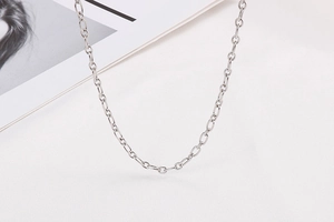 Detailed view of a minimalist silver link chain laying on a neutral aesthetic background