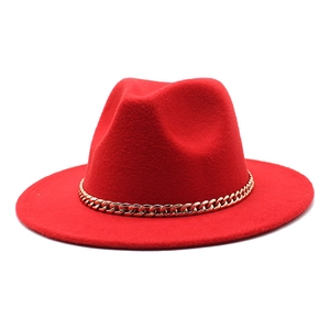 Detail of red fedora hat with a bold gold Cuban chain strap on a wool felt brim