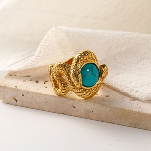 Vintage 18k gold snake ring featuring turquoise stone on beige stone pedestal