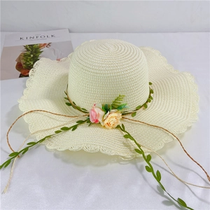Detail of straw sun hat with wavy brim and realistic pink and yellow rose decorations