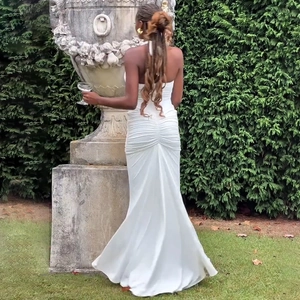 Vue arrière détaillée d'une robe longue blanche à dos nu avec détails plissés au jardin