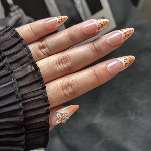 Detail of French almond nails with leopard print and a 3D metal flower with a red rhinestone
