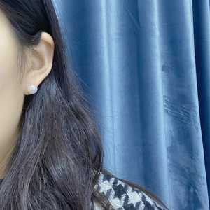 Close-up of a minimalist white freshwater pearl stud earring worn by a model