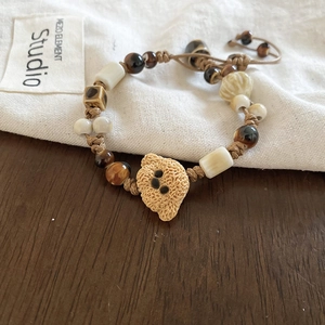 Detail of handmade ceramic bear bead bracelet with woven cord on a wooden background