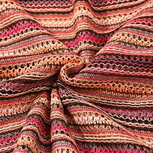 Macro shot of colorful wave-pattern knit fabric with orange, pink, and white stripes