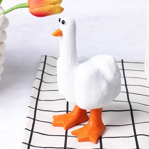 Close-up of a funny resin white duck figurine with orange beak on checkered background