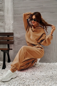 Detailed view of women's tan hoodie and sweatpants set worn in a stylish street pose