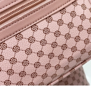 Close-up of pink leather coin purse with brown clover pattern and litchi texture