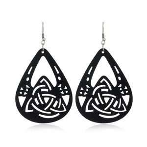 Close-up of black teardrop wooden earrings with Celtic Triquetra laser-cut pattern