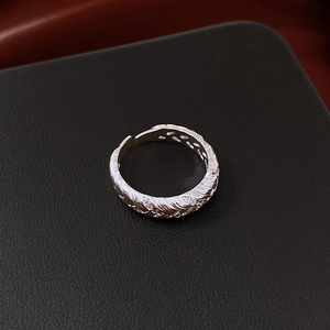 Macro shot of silver feather texture ring with micro-inlaid zircons on black leather
