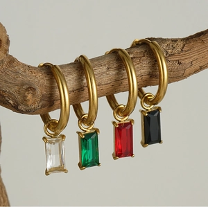 Détail de créoles en or 18 carats avec zircons colorés suspendus à une branche de bois