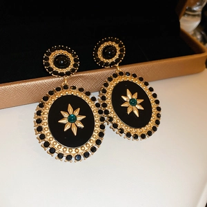Detail of vintage oval earrings with gold starburst and green crystal on black base