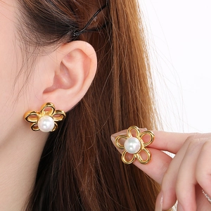 Elegant gold flower earrings with central pearls and zircon inlays shown on model