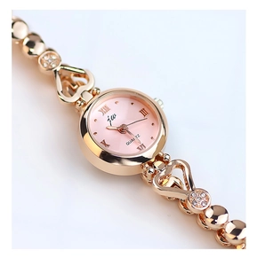 Detail of pink dial quartz watch with heart-shaped gold strap and crystal accents
