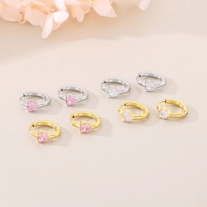 Detailed close-up of heart-shaped zircon hoop earrings in gold and silver finishes
