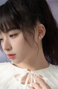 Model wearing small 925 silver flower stud earrings in blue and orange floral design