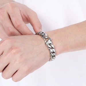 Detailed view of a silver 12mm Cuban curb chain bracelet with secure lobster clasp on wrist