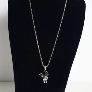 Detailed close-up of astronaut pendant with black stone inlay on silver titanium steel chain
