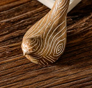 Macro detail of bird ornament showing realistic wood-carved texture and fine white grain