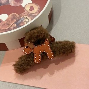Brown plush claw clip with leather puppy detail on pink cardstock background