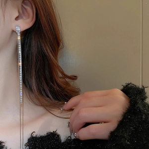 Detail view of elegant silver tassel earrings with zircon crystals worn by a model