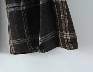 Detailed view of the plaid shirt cuff featuring high-quality fabric and a black button