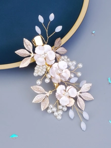 Close-up of handmade bridal hair clip with pink flowers, pearls, and golden leaves