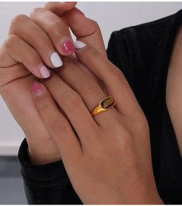 Nahaufnahme eines 18k vergoldeten Titanrings mit einem rechteckigen Tigerauge-Stein