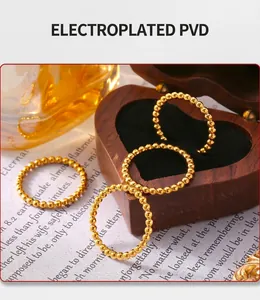 Detail view of gold PVD plated beaded stackable rings on a decorative background