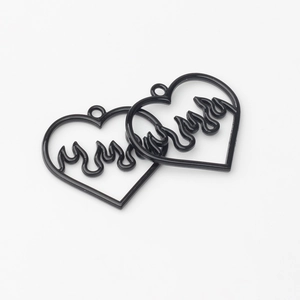 Detail of two black heart-shaped hollow charms with flame patterns for DIY jewelry