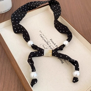 Detailed shot of a French vintage necklace with black polka dot fabric and white pearls