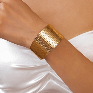 Close-up of golden wide open cuff bracelet with hammered texture on model wrist