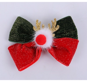 Detail of velvet Christmas bow hair clip with gold glitter antlers and white pom-pom