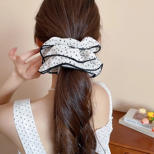 Detail of a large black and white polka dot scrunchie with layered lace edges on hair