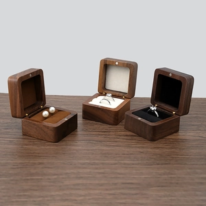 Walnut wood jewelry box collection for rings and earrings on dark wooden surface