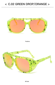Detail of neon green frame with black ink splatters and orange gradient lenses