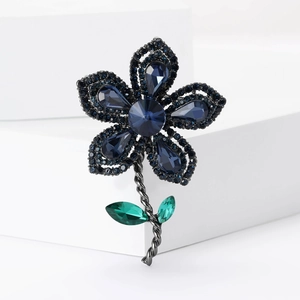 Vue détaillée de la broche fleur de luxe avec cristaux bleus et feuilles vertes sur métal