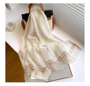 Detail of a beige silk wool blend scarf featuring elegant metallic gold stripes decoration