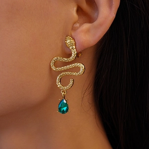 Macro shot of gold snake earring featuring a vibrant emerald green waterdrop pendant