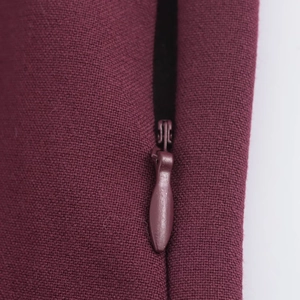 Détail d'une fermeture éclair invisible sur une robe polo plissée bordeaux