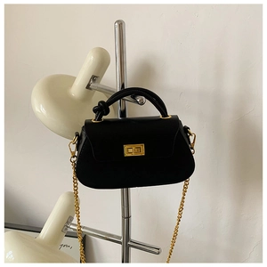 Detail of black handbag showing gold twist lock and unique knotted handle design