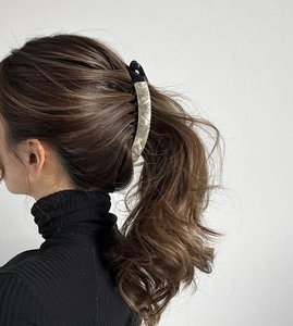 Close-up of a large cream marble banana clip securing a ponytail on long brown hair