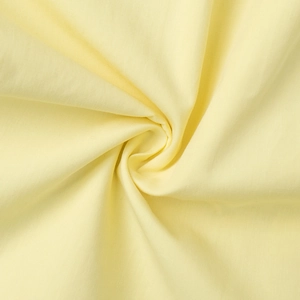 Close-up of light yellow cotton blend fabric texture with soft drapery for summer sets