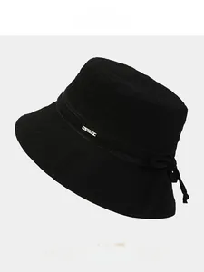 Détail du chapeau bob noir avec plaque en métal Lucky sur une bande en tissu
