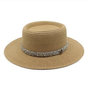 Macro shot of straw hat with rhinestone band and metallic M badge detail
