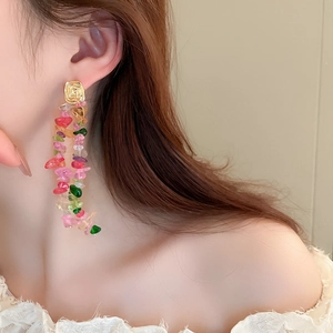 Detail view of long tassel earrings with candy-colored stones on a female model