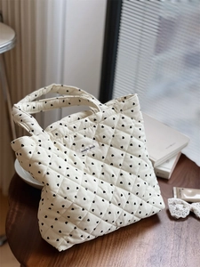 Détail du sac cabas en velours côtelé matelassé avec motifs de cœurs noirs et étiquette