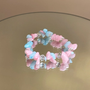 Macro detail of aquamarine camellia beaded elastic bracelet with pink and blue stones